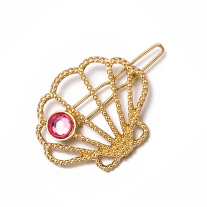 Golden shell hair clip with pink gemstone on white background for women