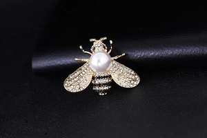 Macro view of bee brooch showing detailed white pearl inlay and sparkling rhinestone wings
