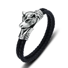 Detail of men's black braided leather bracelet with silver wolf head metal buckle closure