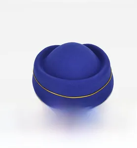 Macro detail of royal blue wool uniform hat featuring minimalist gold cord trim