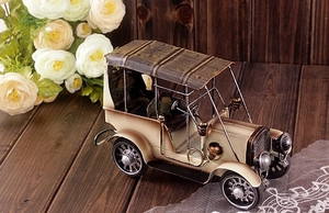 Détail d'un modèle de voiture rétro en métal crème avec finition vieillie sur bois