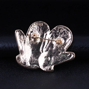Rear view of Christmas glove and snowflake brooch pin with golden textured finish