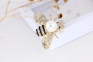 Detailed view of an elegant bee brooch with sparkling crystals and a large white pearl