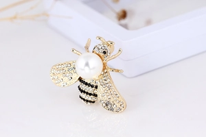 Macro shot of 3D bee brooch with white pearl, gold plating, and sparkling rhinestones
