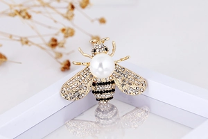 Macro detail of bee brooch with golden wings, white pearls and sparkling rhinestones