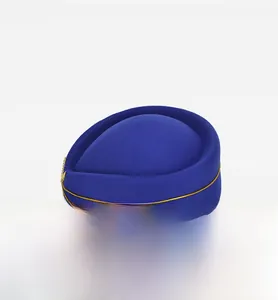 Close-up of royal blue pillbox hat featuring gold trim and decorative emblem on side