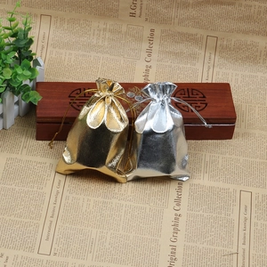 Close-up of gold and silver metallic drawstring pouches on an ornate vintage wooden box