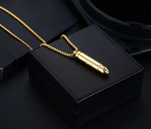 Macro detail of golden bullet pendant with cross engraving on stainless steel box chain