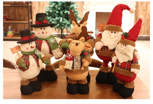 Close-up of plush Christmas snowman and reindeer dolls on a festive wooden table