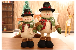 Close-up of plush Christmas snowman decorations with Let It Snow sign in a cozy setting