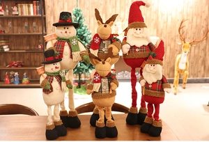 Detail of telescopic Christmas plush toys with snowman, reindeer, and Santa Claus on wood table
