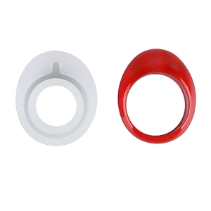 Dettaglio di anello in resina rossa accanto allo stampo in silicone fai-da-te su bianco