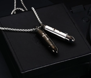 Close-up of black and silver bullet pendant urn necklaces with engraved cross detail
