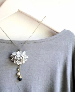 Detailed view of a retro floral necklace pendant with pearls and black teardrop beads on a chain