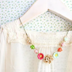 Detailed view of resin flower necklace on vintage bronze chain with lace fabric background