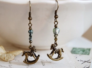 Close-up of vintage bronze rocking horse earrings with light green translucent beads