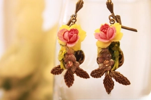 Detailed macro view of vintage floral resin earrings with pink rose and bronze leaf design