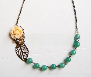 Close-up of a vintage bronze necklace featuring a resin rose and metallic leaf detail