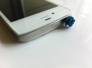 Detailed view of a blue 3D resin rose flower dust plug on a white smartphone