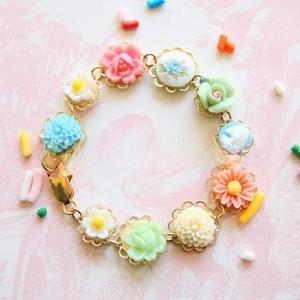 Detail of a floral charm bracelet with colorful resin roses and a vintage cameo pendant
