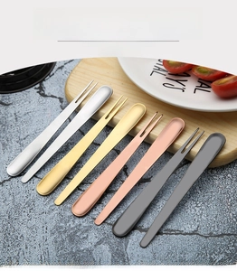 Close-up of golden and silver stainless steel dessert spoons and forks on a wooden board