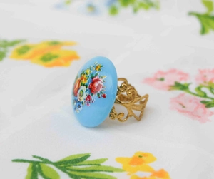 Detailed close-up of a vintage-style ring with blue floral pattern and golden镂空 band