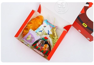 Overhead view of a Christmas gift box filled with snacks, cookies and festive greenery