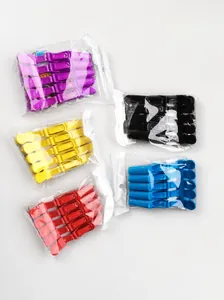 Five sets of colorful plastic crocodile hair clips in transparent bags on a grey floor