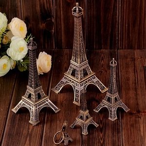 Detailed close-up of bronze Eiffel Tower replicas in various sizes on dark wood background