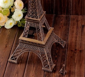 Detail of vintage bronze Eiffel Tower model and miniature keychain on rustic wood surface