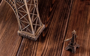 Detailed macro view of vintage bronze Eiffel Tower model and keychain on wooden surface