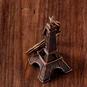 Macro shot of bronze Eiffel Tower alloy pendant with France engraving on wood background
