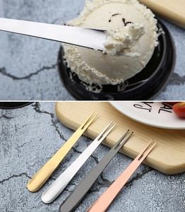 Close-up of gold, silver, and black stainless steel fruit forks on marble surface