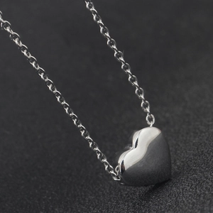 Macro shot of silver stainless steel heart pendant on fine O-chain with smooth finish