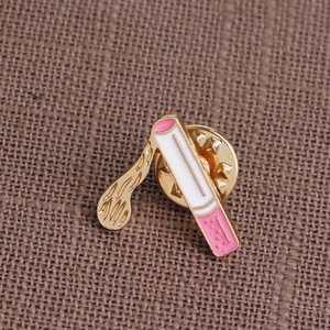 Detail of cartoon cigarette enamel brooch with pink filter and gold metal plating