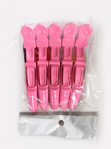 Detail of five pink professional crocodile hair clips packaged in clear self-adhesive bags