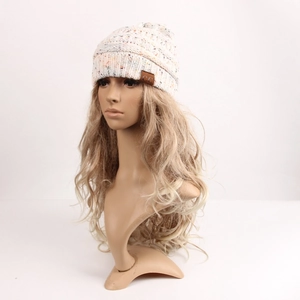 Detailed close-up of cream knit beanie with colorful flecks and a leather brand label