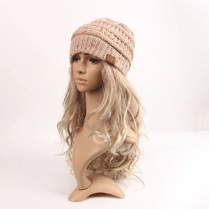 Detail of coarse knit beige beanie texture and brown leather C.C brand label on the side