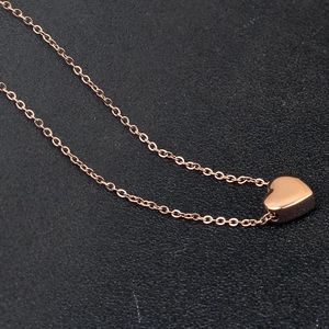 Detailed close-up of a rose gold heart pendant necklace on a black textured background