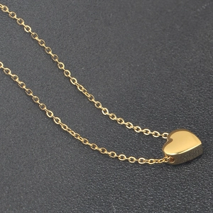 Detailed view of a small 18K gold heart pendant on a delicate O-chain link necklace
