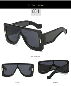 Detail of square oversized futuristic sunglasses with gold accents and dark grey lenses