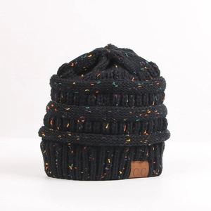 Close-up of black cable knit beanie with colorful flecks and brown leather brand label