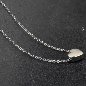 Macro shot of 3D silver heart pendant with polished stainless steel finish and fine chain