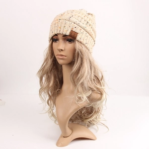 Detailed close-up of beige knitted beanie featuring colorful flecks and a C.C leather patch