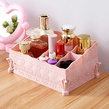 Close-up of pink plastic makeup organizer with textured compartments on wooden desk