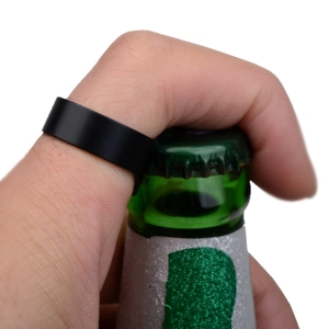 Close-up of black stainless steel ring functioning as a bottle opener on a green glass bottle