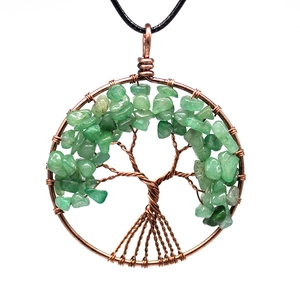 Macro detail of handmade copper wire tree of life pendant with green gemstone leaves