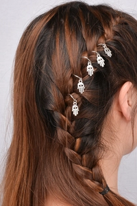 Detail of silver Hamsa hand charms woven into braided hair for stylish DIY hair decoration