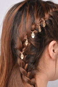 Macro shot of five golden Hamsa hand charms on a braided hairstyle for DIY hair styling