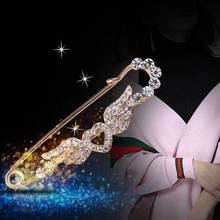 Detail of a golden heart wing safety pin brooch with rhinestones on a pink cardigan